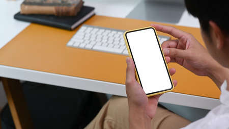 View over shoulder of casual businessman using smart phone at office.