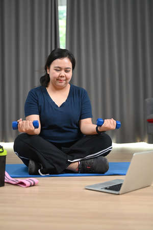 Overweight women tying shoelaces getting ready for exercise.の写真素材