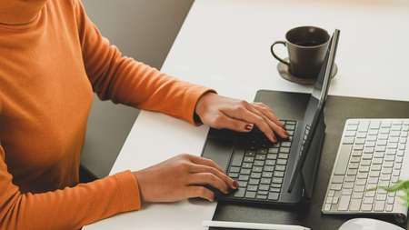 Cropped shot of stylish woman hands typing on wireless keyboard of digital tablet.