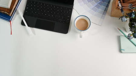 Top view modern workspace with digital tablet, laptop, coffee cup and notebook on blue leather.