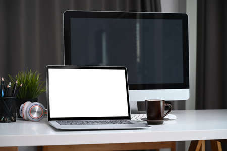 Top view of white office desk with coffee cup, glasses, notebook and plant.