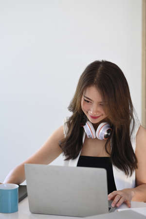 Portrait of smiling young female working online with laptop computer.