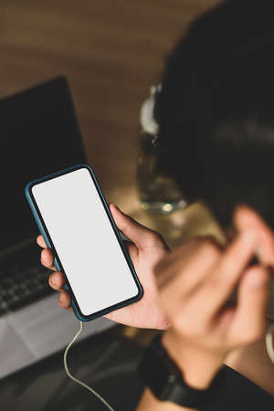 Close up view of man listening music on smartphone while exercising in living room.の写真素材