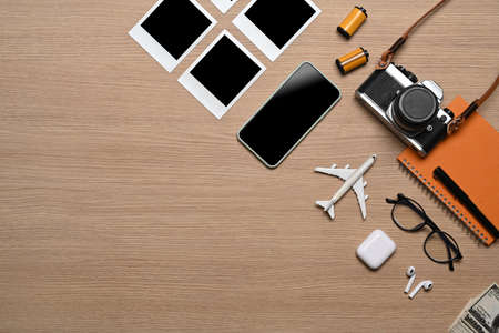 Above view of smart phone and travel accessories on wooden background. Vacation concept.