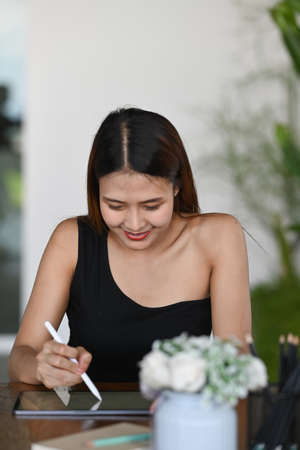 Cheerful asian woman talking on mobile phone while sitting in cafe.