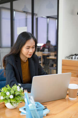 Friendly female coffee shop owner in apron showing digital tablet. Blank screen for advertising text.の写真素材