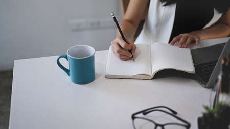 Close up view businesswoman holding mock up mobile phone with lank screen at her workspace.の写真素材