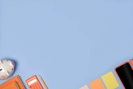 Above view mobile phone, keyboard and notebook on blue background.