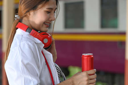 Young female traveller checking time on her smartwatch and waiting train at station.