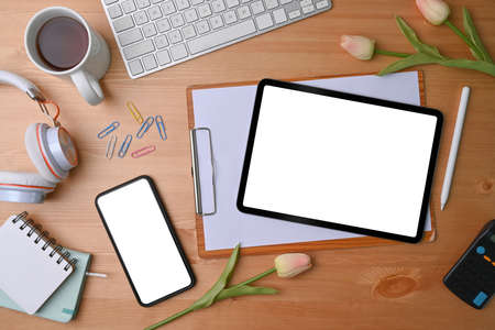 Top view stylish workplace with notebook, glasses, coffee cup, mobile phone and pen on red...