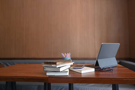 Overhead shot of modern workspace with digital tablet, wireless earphone, coffee cup and notebook on...