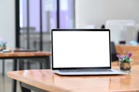 Laptop computer with white screen on wooden desk in modern office.の写真素材