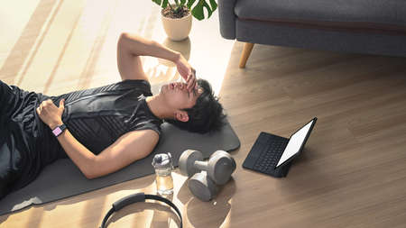 Cropped shot of young man using laptop computer and making note on notebook while sitting on sofa.