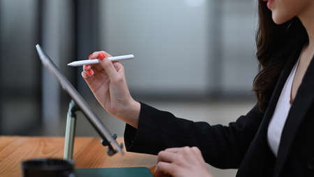 Happy businesswoman in suit sitting at modern workplace and smiling to camera.