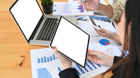 Cropped shot of businesswoman using digital tablet and discussing new project with her colleagues.