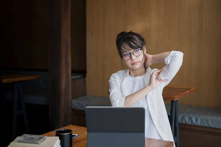 Cheerful female student sitting in library with laptop computer and smiling to camera.