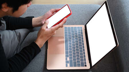 Asian man sitting on couch and surfing internet with laptop computer.