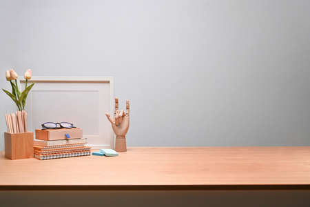 Empty picture frame, houseplant, and office supplies on wooden table.の写真素材