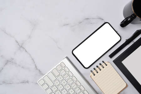 Empty picture frame, houseplant, and office supplies on wooden table.