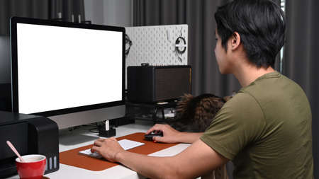 Young man using mobile phone and laptop while lying on couch.の写真素材