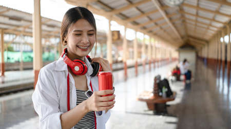 Happy female with her camera standing on platform and waiting for the train.