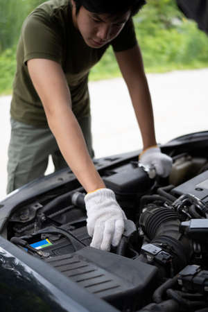 Back view of young man sitting in living room and using mobile phone.の写真素材