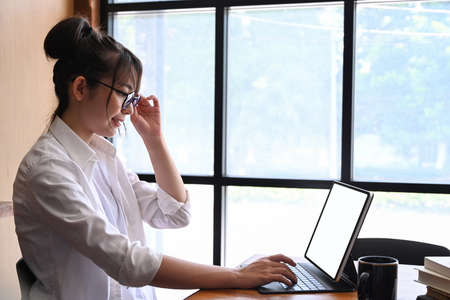 Side view of female designer sitting in office and working with computer tablet.の写真素材