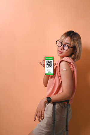 Happy female wearing face mask holding mobile phone and showing her vaccinated arm.の写真素材