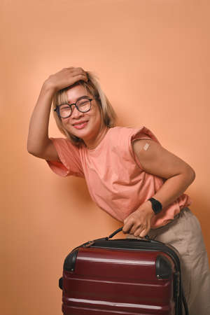 Happy young woman traveler showing her arm after receiving a vaccine.の写真素材