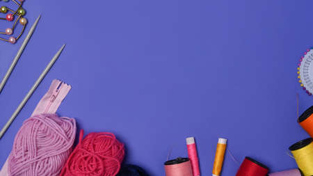 Top view sewing tools on purple background.