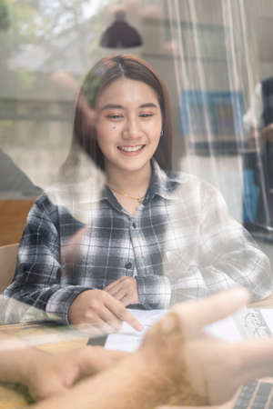 Young woman designer sitting in office with her laptop computer and smiling to camera.の写真素材
