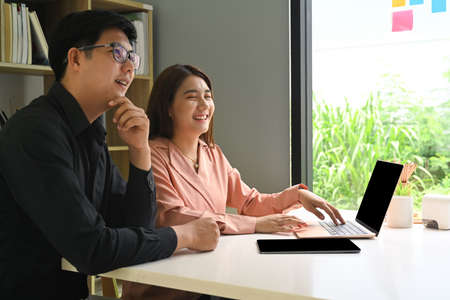 Young businesspeople sitting in modern office and smiling to camera.の写真素材