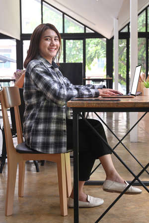 Full length portrait of  happy businesswoman sitting in office and smiling to camera.