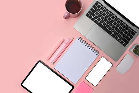 Graphic designer workspace with laptop, smart phone, glasses and notebook on pink background.