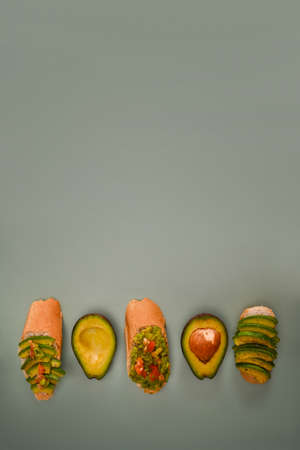 Whole and half avocado on green background.