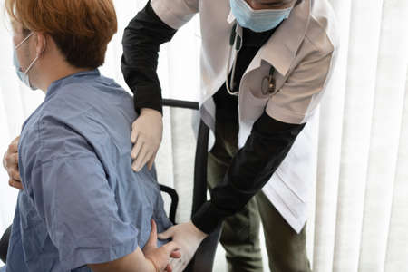 Doctor examining a patient suffering from back pain.の写真素材