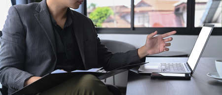 Smart businessman working with laptop and reading report in office.