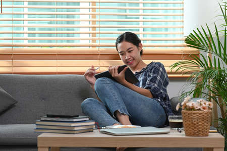 Smiling woman architect working at home with blueprint and digital tablet.