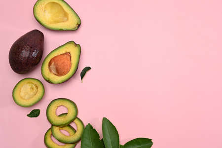 Half avocado on pink background.