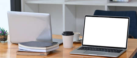 Computer laptop, coffee cup and documents on wooden tale in meeting room.