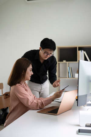 Two young business people discussing business idea in modern office.の写真素材