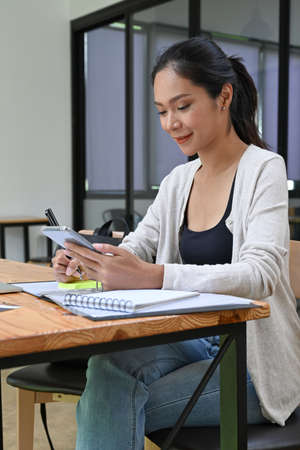 View through glass window of young woman working in modern coffee shop.
