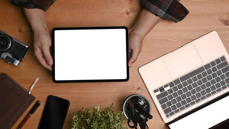 Man photographer holding digital tablet on wooden desk.