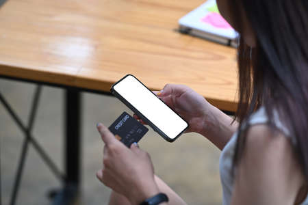Woman hands holding credit card and using smart phone for banking online or online shopping.