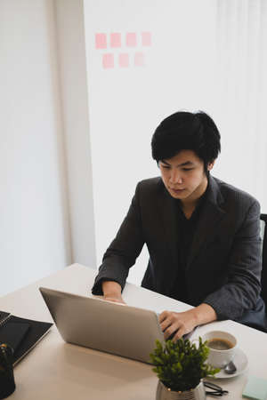 Cropped shot businessman in suit using mobile phone at office desk.の写真素材