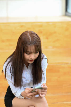 Female office worker holding notebook and working with laptop computer.