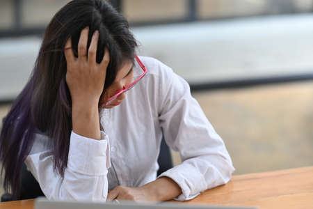 Fatigued businesswoman sitting at her desk in office.