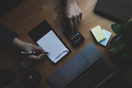 Top view female working with laptop and making note on notebook.の写真素材