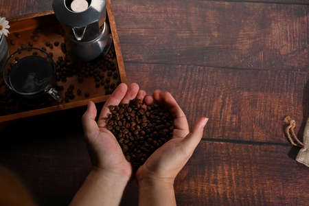 A cup of coffee and coffee beans on rustic wooden background.