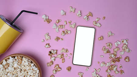 Mock up mobile phone with blank screen and popcorn on pink background.